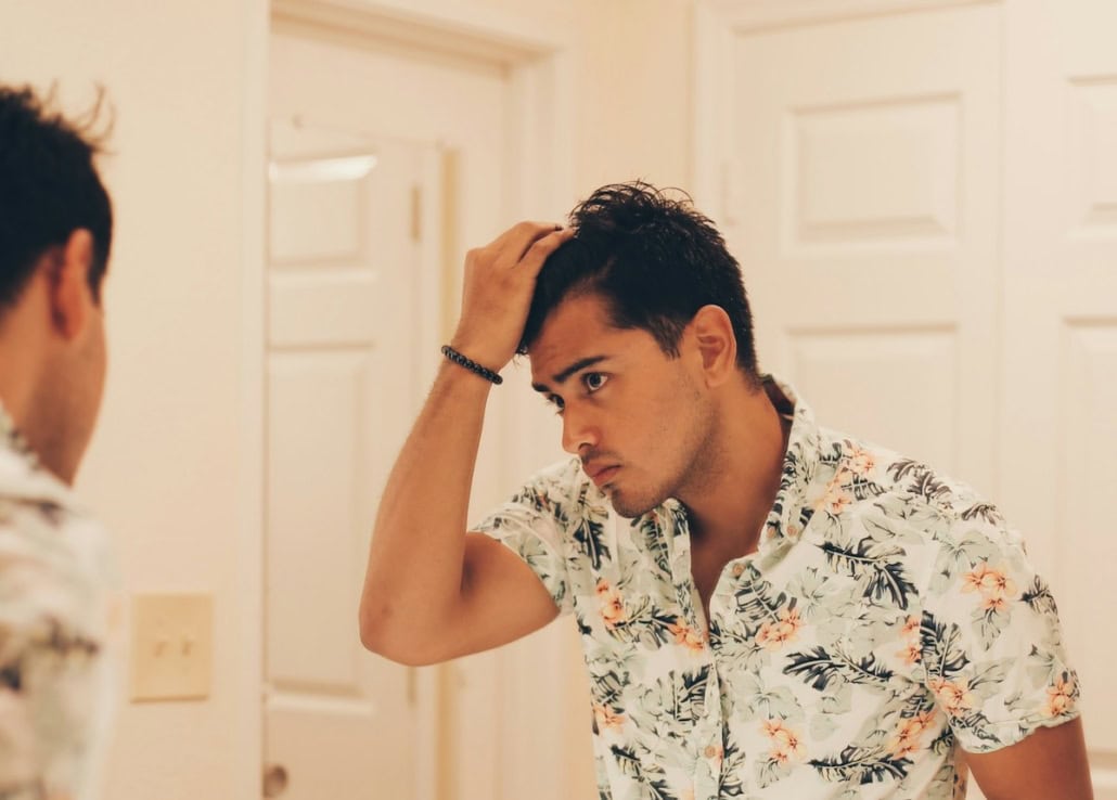 Man checking his thinning hair in the mirror before PRP hair treatment